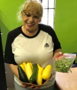woman holds display of vegetables